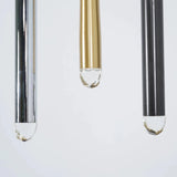 Chandelier detail showing silver, brass, and black tubes with clear faceted crystal tips against a pale background.