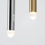 Chandelier detail showing silver and brass tubes with glowing crystal tips suspended at different heights against pale gray.