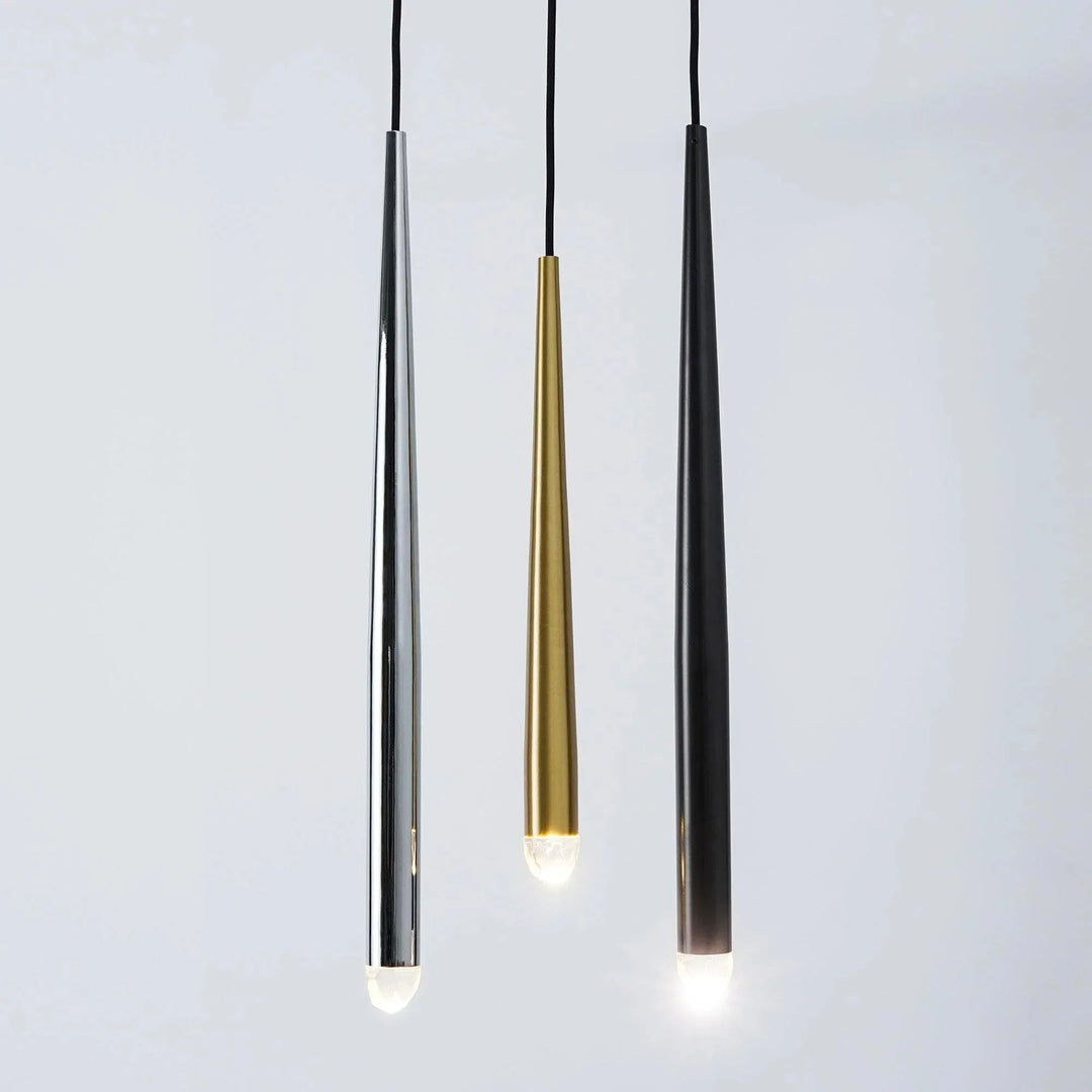 Three tapered chandelier tubes in silver, gold, and black finishes hang against a pale gray background with illuminated crystal tips.
