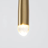 Close-up of a chandelier brass tube with an illuminated crystal tip against a pale gray background.
