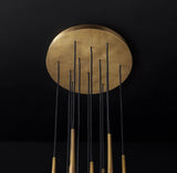 Chandelier canopy detail with a round brass ceiling plate and multiple black suspension cords against a black background.