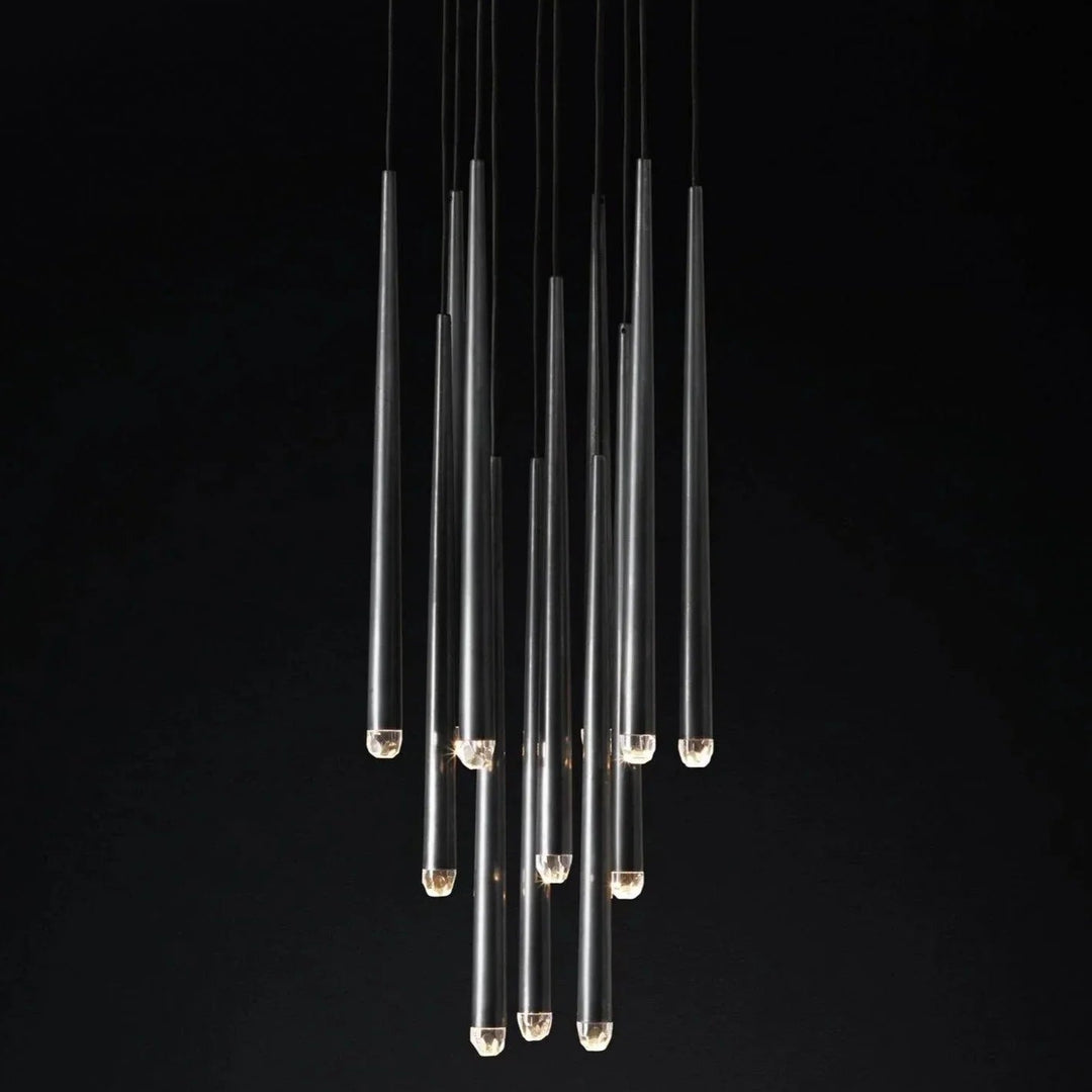 A modern multi-light linear chandelier with clear glass tubes suspended at varying lengths against a solid black background.