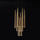A modern multi-light linear chandelier with brushed gold metal tubes suspended by thin black cords against a solid black background.