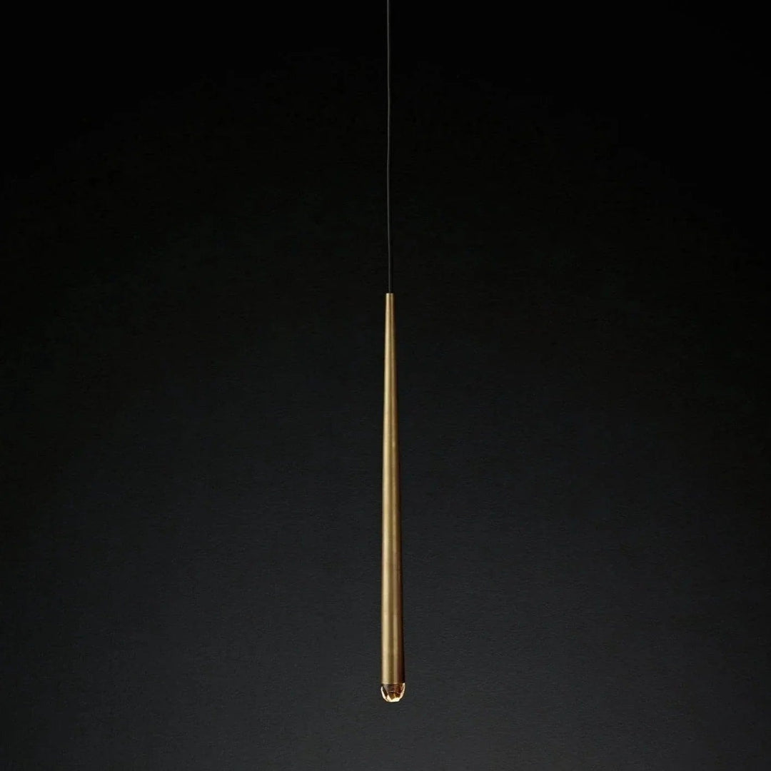 Chandelier detail showing a tapered brass tube with a clear crystal tip suspended against a dark background.