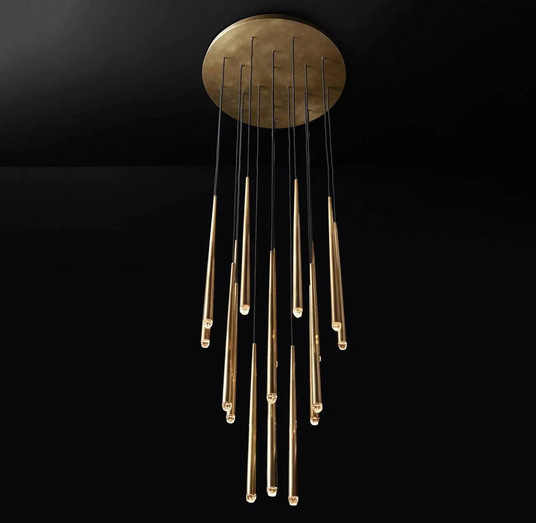 A modern chandelier with a circular brushed brass ceiling canopy and multiple vertical glass tubes in varying lengths, shown against a solid black background.