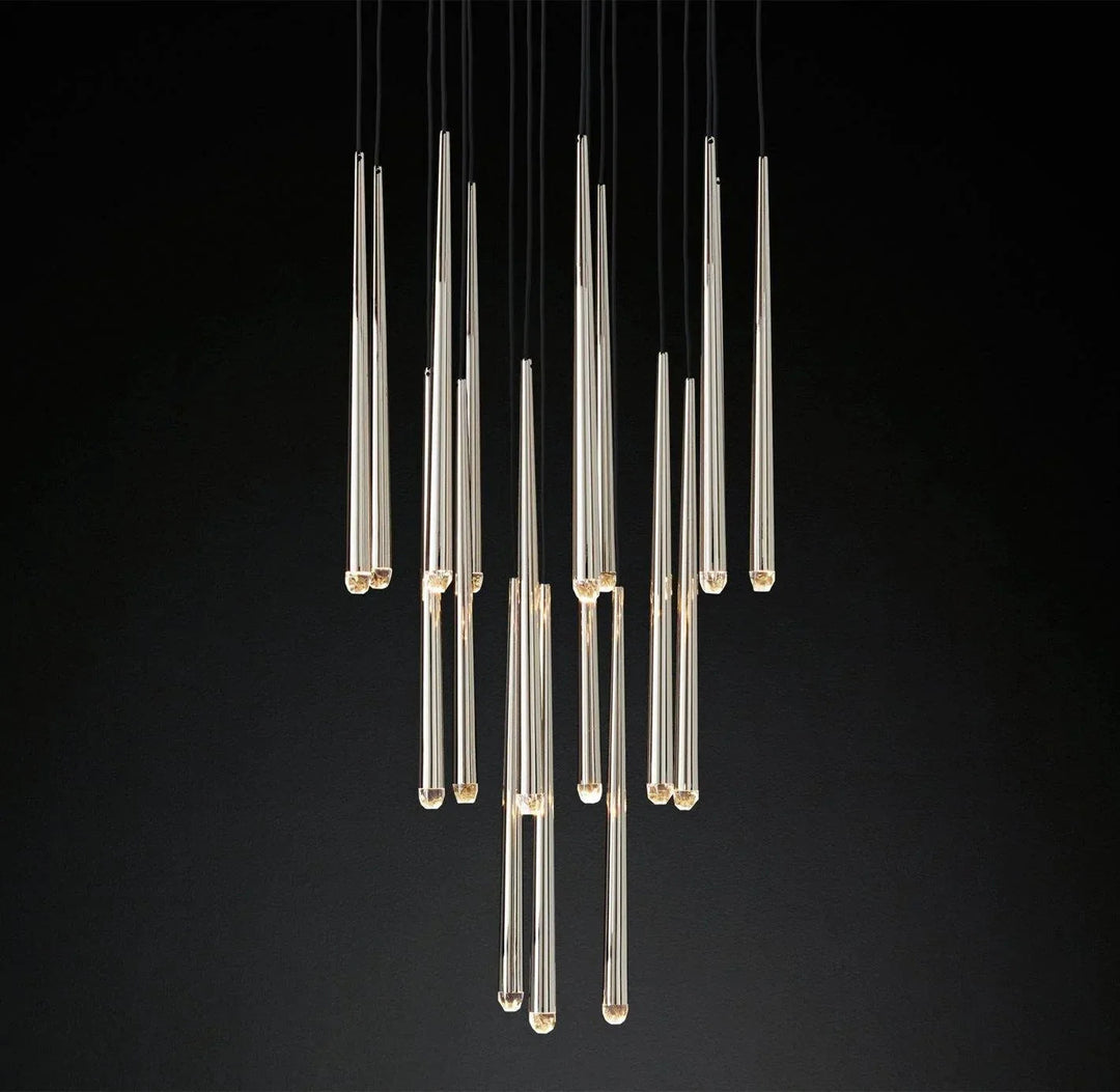 Brass and crystal tube chandelier with slender drops suspended at staggered heights against a black background.