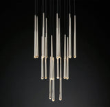 Brass and crystal tube chandelier with slender drops suspended at staggered heights against a black background.