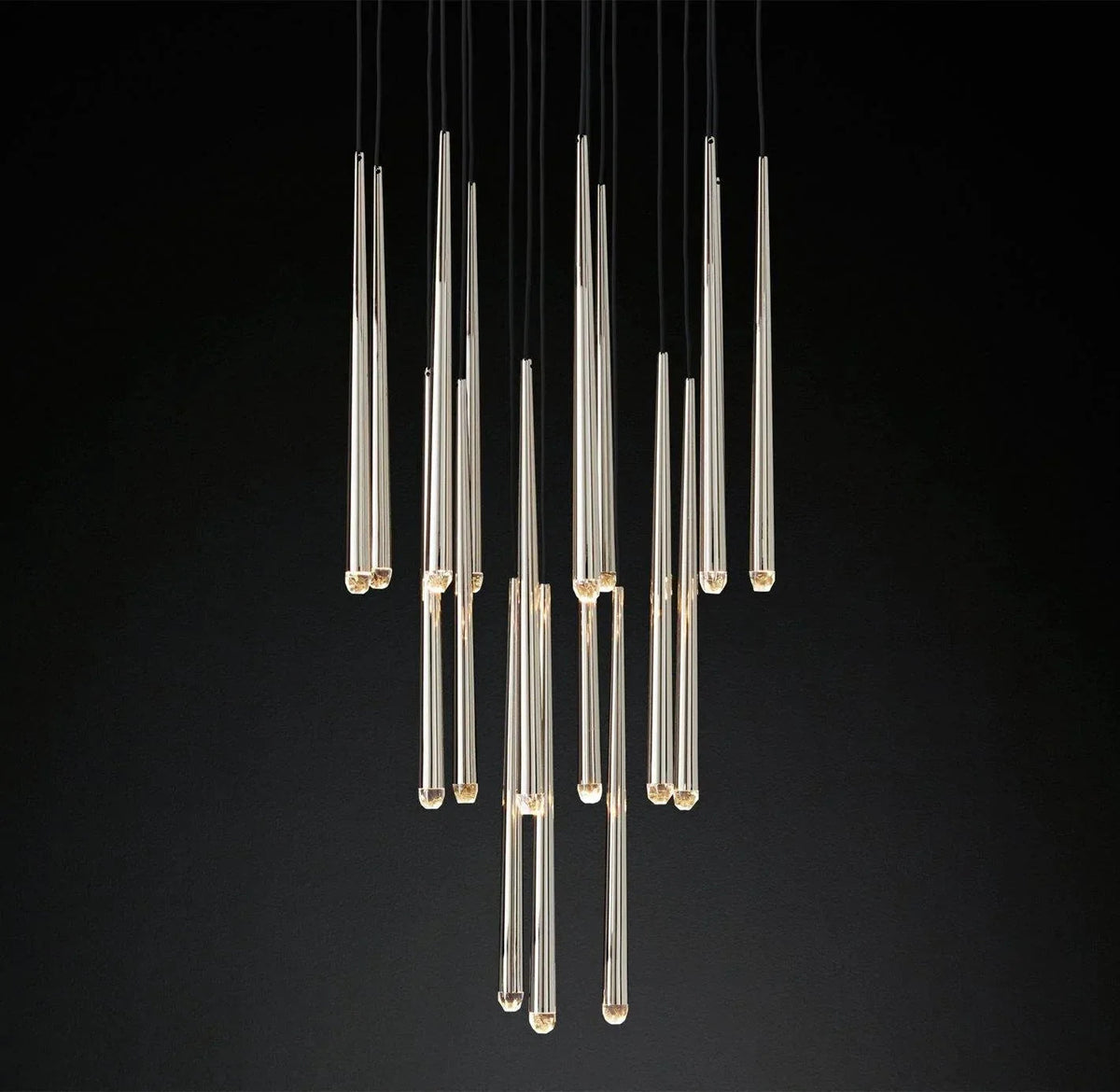 Brass and crystal tube chandelier with slender drops suspended at staggered heights against a black background.