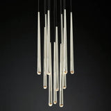A modern multi-light chandelier featuring multiple clear glass cylindrical tubes of varying lengths suspended from black cords against a solid black background.