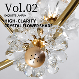 Close-up of the gold chandelier with clear faceted crystal flower petals and gold centers against a light gray background.