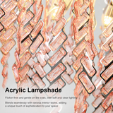 Close-up of the chandelier’s pink acrylic prism fringe with warm light glowing through the pieces against a light gray background.