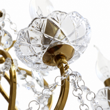 Close-up of the floor lamp’s cut-glass candle cup, antique brass arm, and hanging crystal drops against a white background.