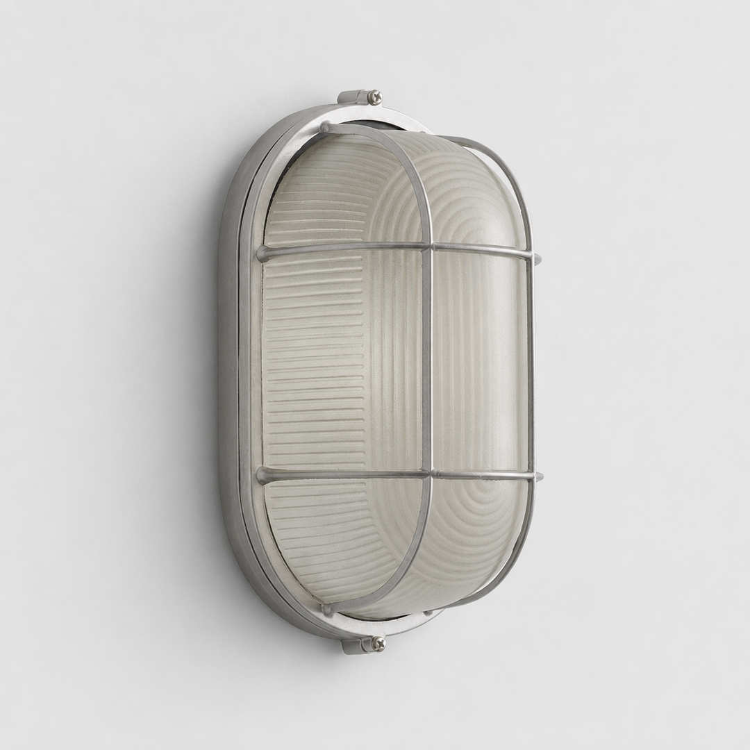 An oval wall sconce with a silver cage frame and ribbed frosted glass is mounted vertically on a light gray wall.