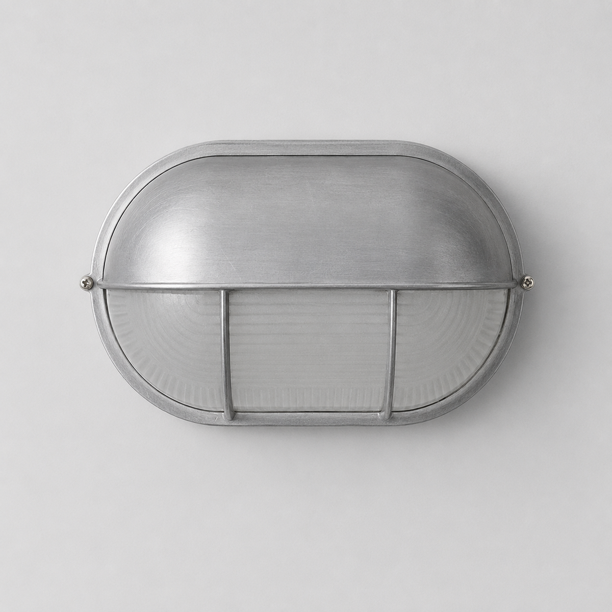 Oval wall sconce with a brushed silver metal hood and ribbed glass diffuser against a light gray background.
