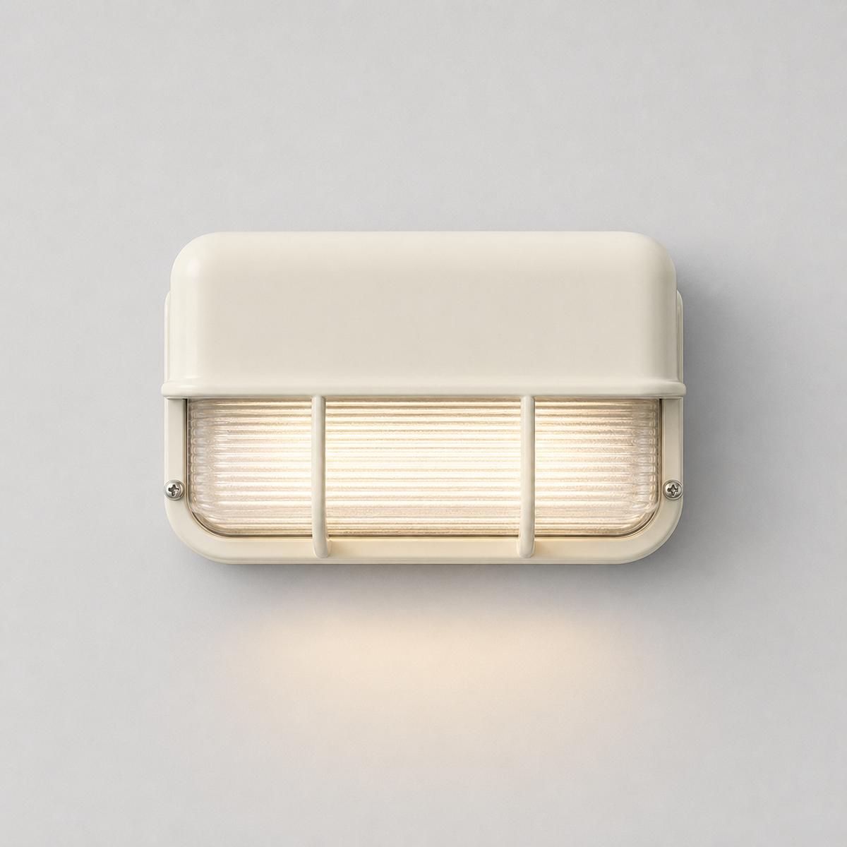 Front view of an illuminated off-white wall sconce with ribbed glass and protective bars, casting warm light onto a gray wall.