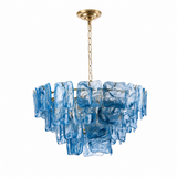 A modern chandelier featuring a tiered arrangement of translucent blue glass blocks suspended from a gold-toned chain and canopy, shown against a plain white background.