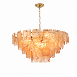A modern tiered chandelier featuring textured, translucent amber-orange glass panels suspended from a gold-finished metal frame and chain.