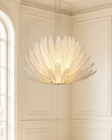 A large, modern chandelier with a sunburst design made of clear textured glass or crystal, suspended from two cables in a classic cream-colored paneled room.