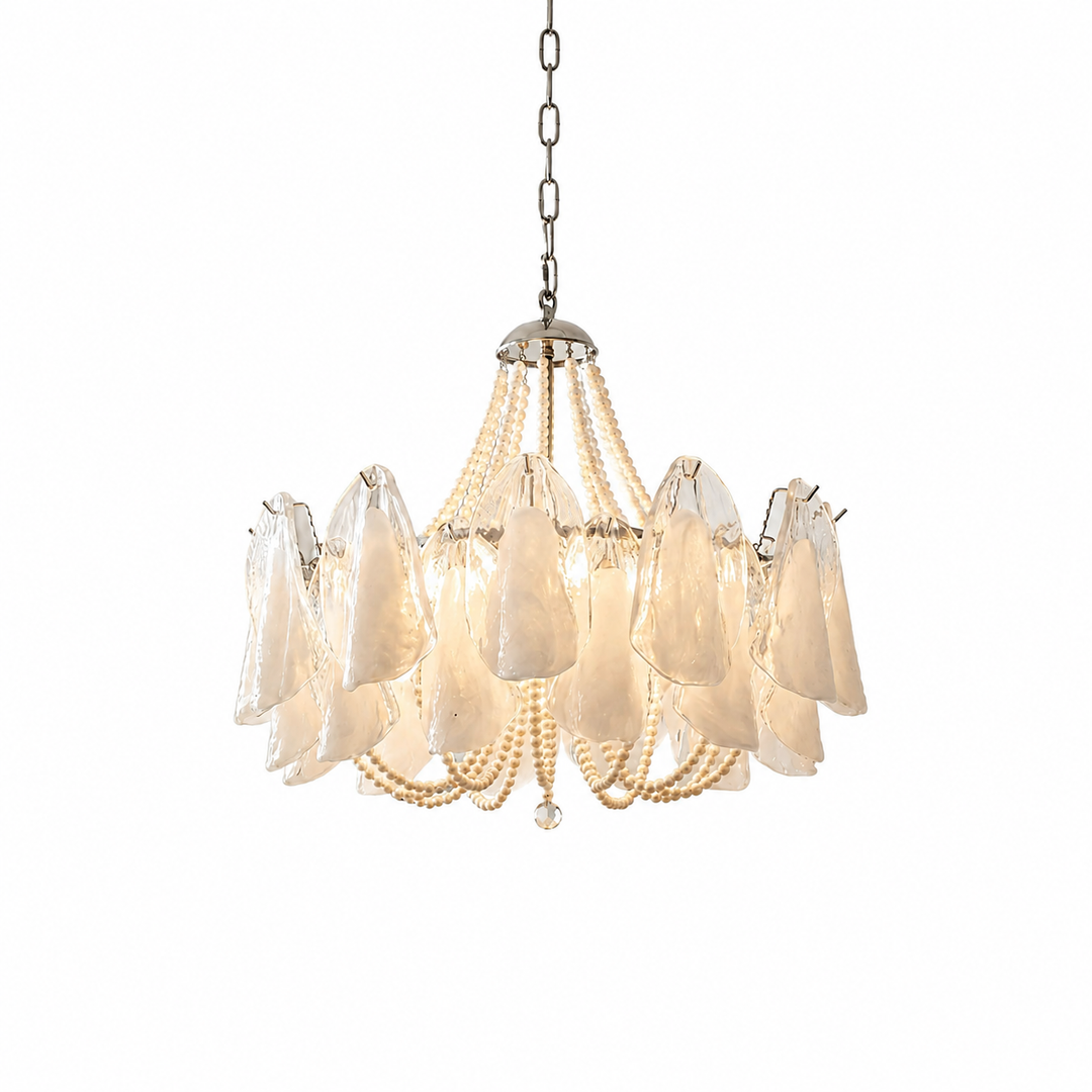 Chandelier with translucent petal-shaped glass shades and cream beaded strands hanging from a silver chain, lit warmly against a white background.