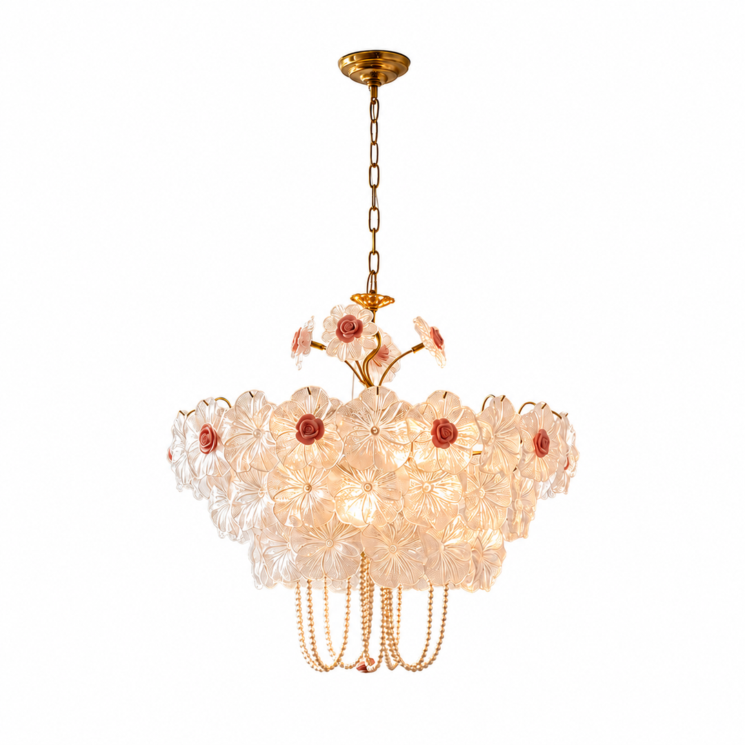 Illuminated floral chandelier with translucent petals, pink rose accents, gold-tone chain and draped beads against a white background.
