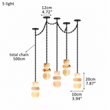 A 5-light pendant chandelier with black metal chains and round, stacked amber and cream glass shades, shown with dimension labels on a white background.