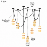 A 7-light chandelier with black metal chains and warm glowing stone shades, shown on a white background with dimension labels indicating 12cm, 20cm, 10cm, and a total chain length of 700cm.
