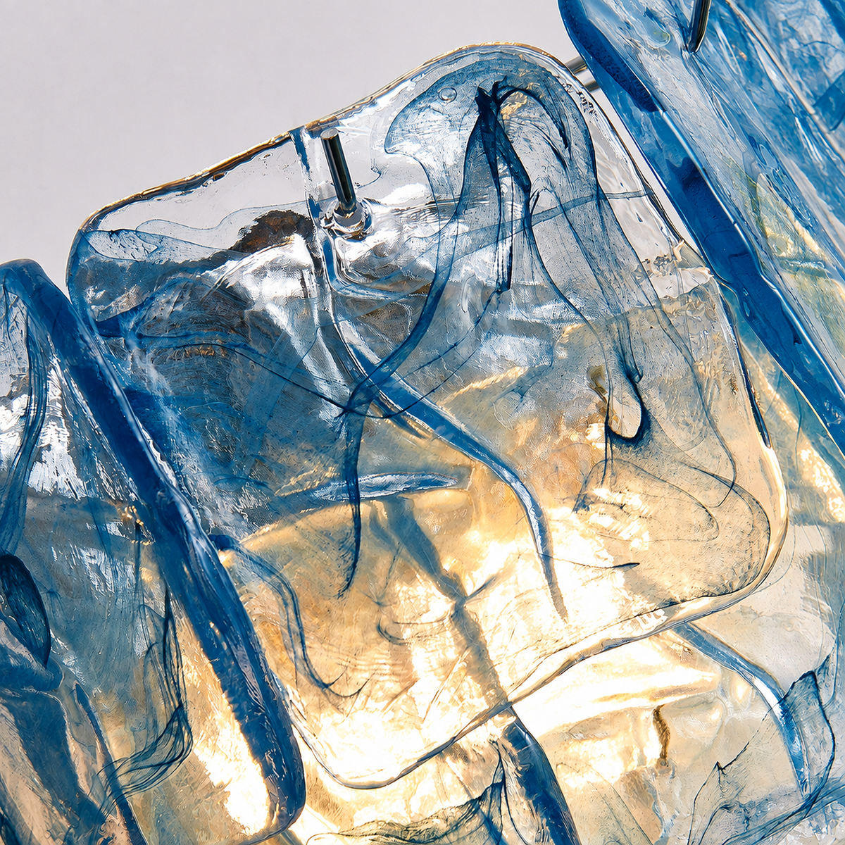 Close-up of the wall sconce showing rippled blue glass panels, metal supports, and warm light shining through.