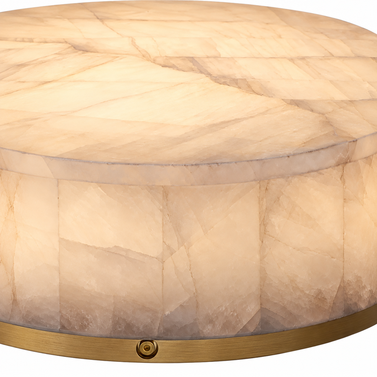 Close-up of an illuminated flush mount light with a cream alabaster drum and gold-toned rim against a white background.
