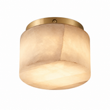 A modern semi-flush mount ceiling light featuring a warm, textured beige glass shade and a brushed brass metal canopy, shown against a solid white background.