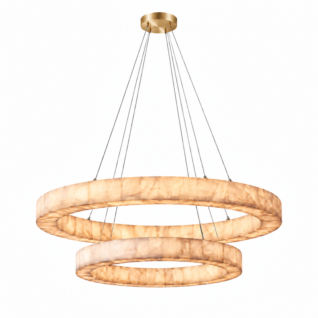 A modern two-ring chandelier pendant light with a warm, textured stone-look finish and a brushed gold ceiling canopy, suspended by thin black cords against a plain white background.