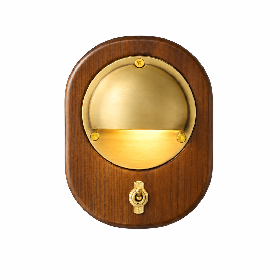 Wall sconce with a brown wood backplate, brass dome shade, and toggle switch, shown illuminated against a white background.