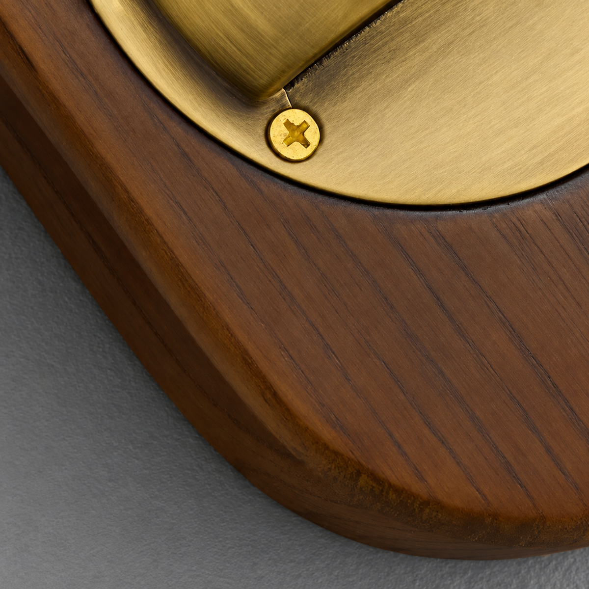 Wall sconce close-up shows the brown wood grain, rounded backplate edge, and brushed brass shade secured with a visible screw.