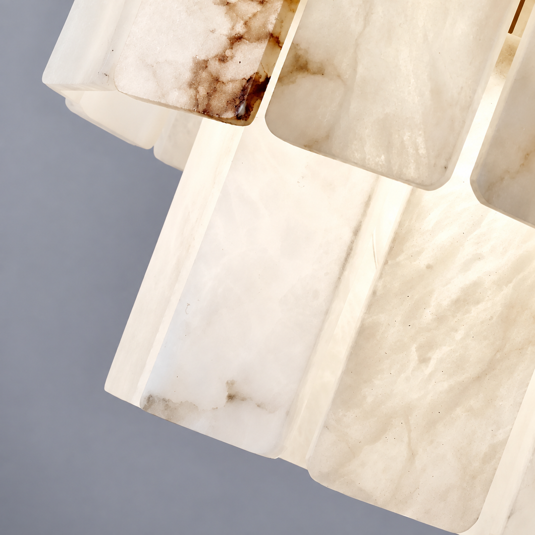 Close-up of a chandelier with overlapping cream alabaster panels, brown veining, and softly illuminated edges against a gray background.
