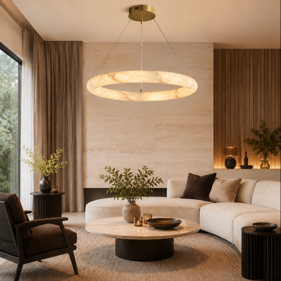 Glowing alabaster ring chandelier with a brass canopy above a round coffee table in a living room with a cream sectional.