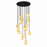 A modern multi-light chandelier with a circular black ceiling canopy and multiple hanging black cords suspending warm, pearlescent glass globes, shown on a plain white background.