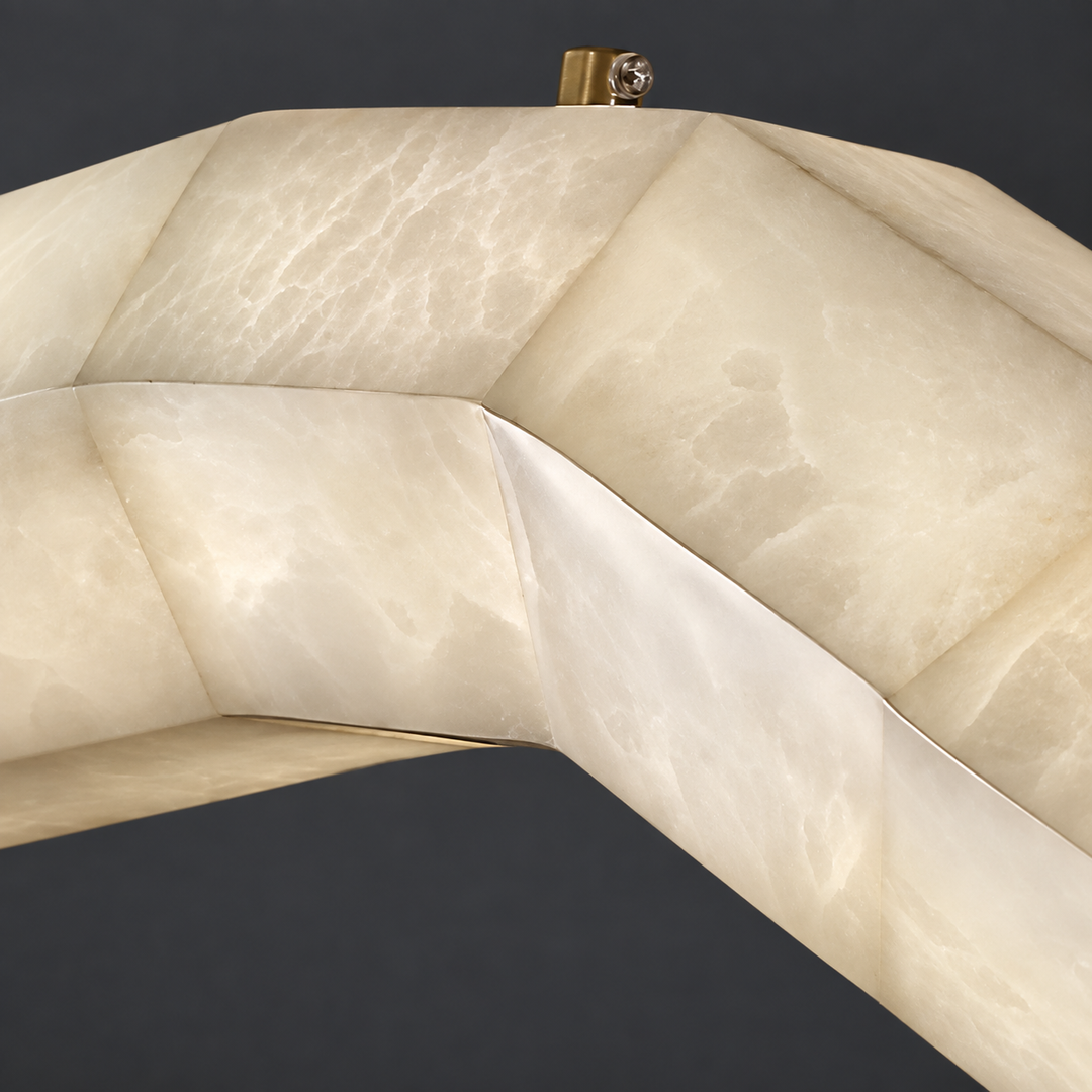 Close-up of a pendant light with cream alabaster veining, a wave-shaped body, and copper hardware against a dark gray background.