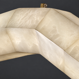 Close-up of a pendant light with cream alabaster veining, a wave-shaped body, and copper hardware against a dark gray background.