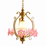 Gold-tone pendant light with pink glass flowers and a glowing frosted bell shade on a white background.