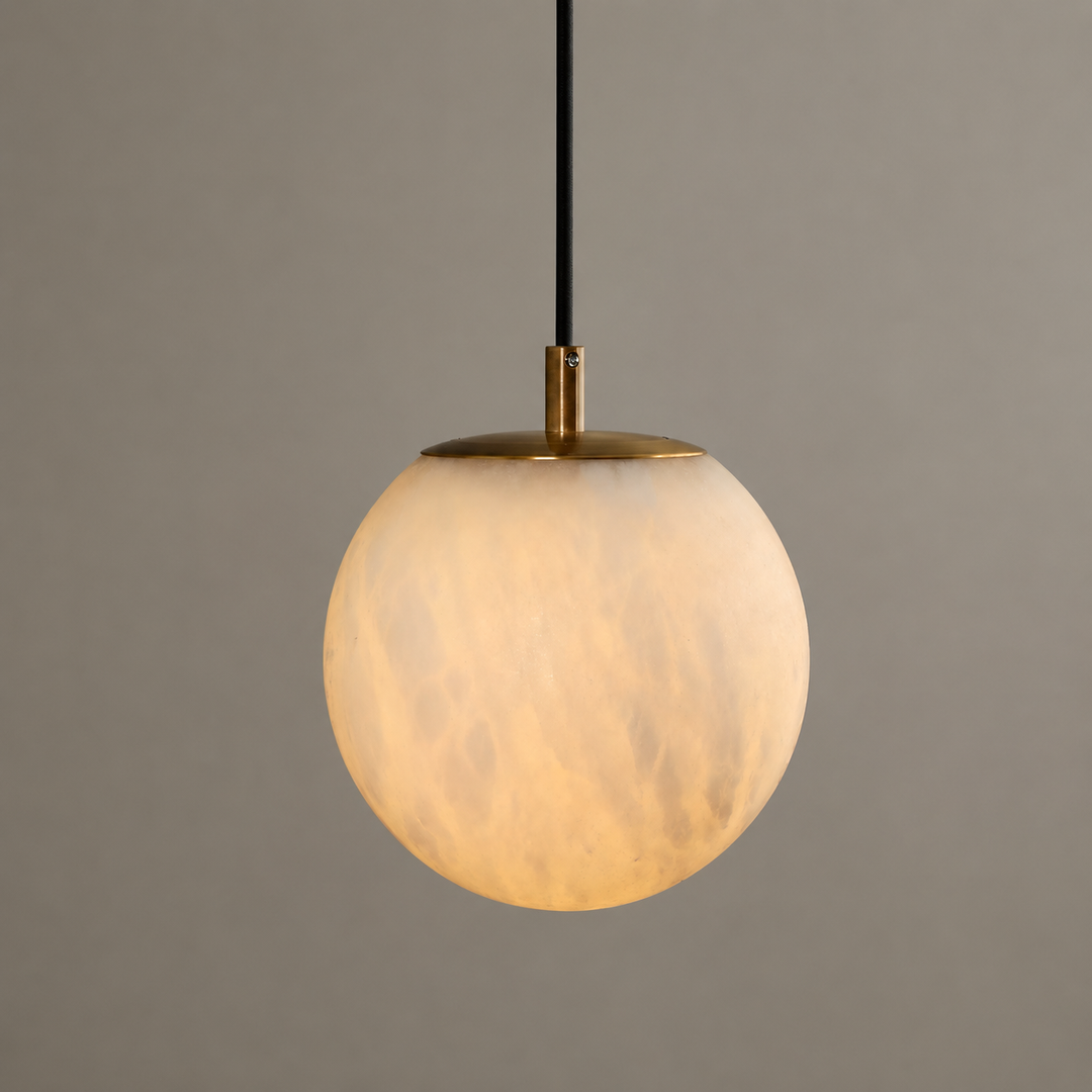 Wall pendant close-up showing a glowing, veined alabaster globe with a brass cap and black cord against a gray background.
