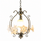 Pendant light with a silver-tone iron frame, cream glass flowers, and a glowing central shade against a white background.