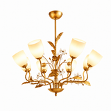 A six-light gold chandelier with a floral vine design, featuring warm white frosted glass shades and small clear crystal accents, shown against a plain white background.