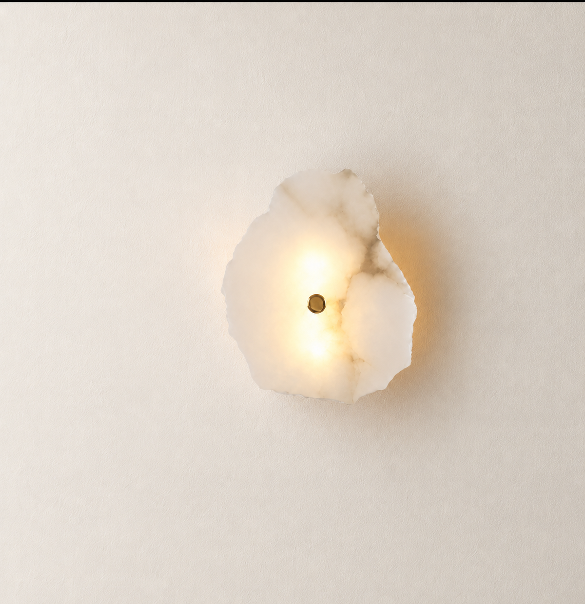 A modern wall sconce featuring a glowing, irregularly shaped white stone or marble slab with a small central brass screw, mounted on a plain off-white wall.