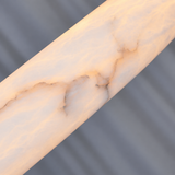 Close-up of the chandelier’s illuminated alabaster ring, showing cream tones and irregular veining against a gray background.