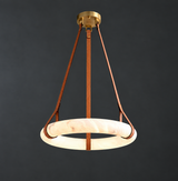 Chandelier with a glowing cream alabaster ring suspended from brown leather straps beneath a brass canopy against dark gray.