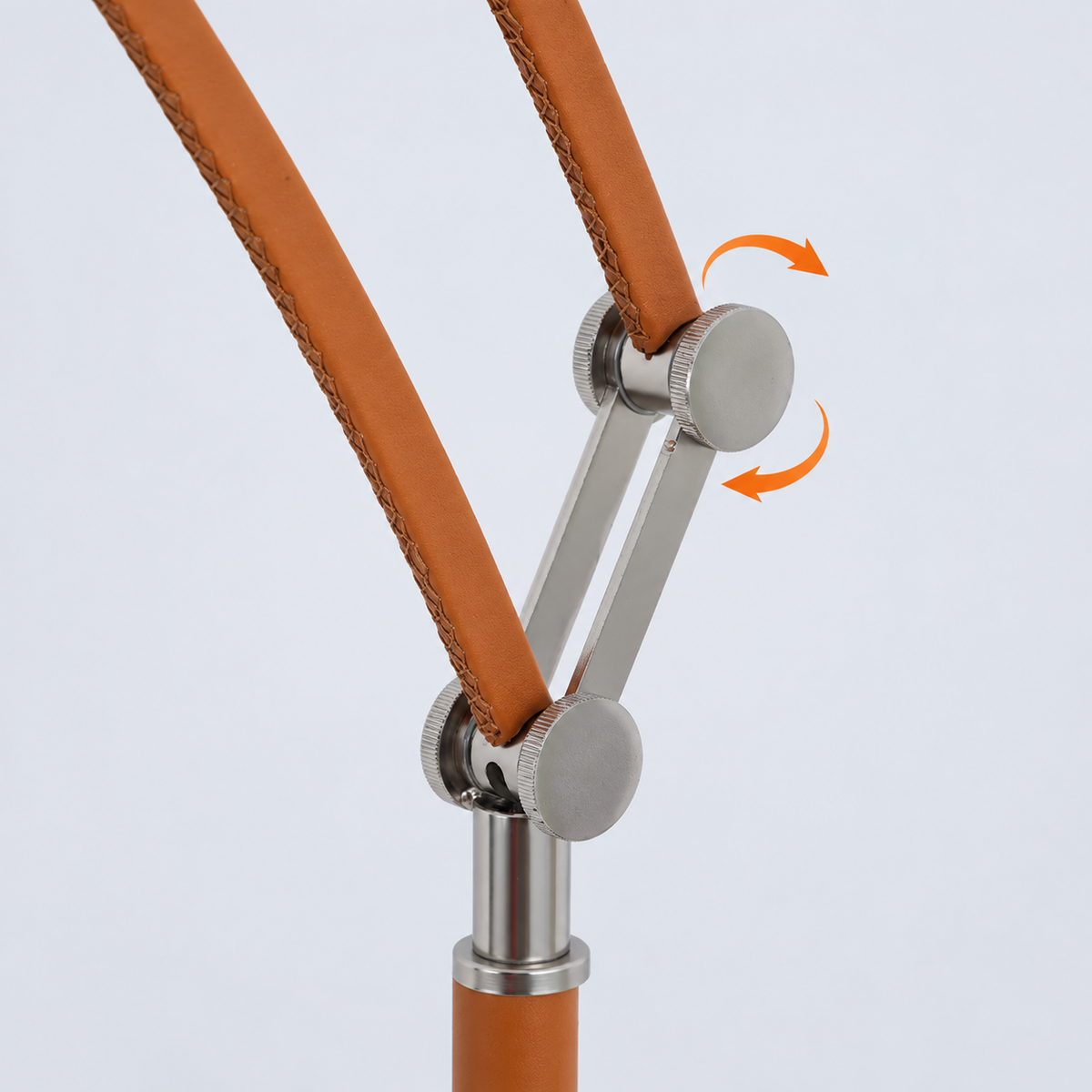 Close-up of the floor lamp’s brown leather-covered arms and silver metal joints, with orange rotation arrows against a pale background.