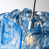 Close-up of a blue marbled glass pendant light with rippled panels around a polished silver-tone frame and central rod.