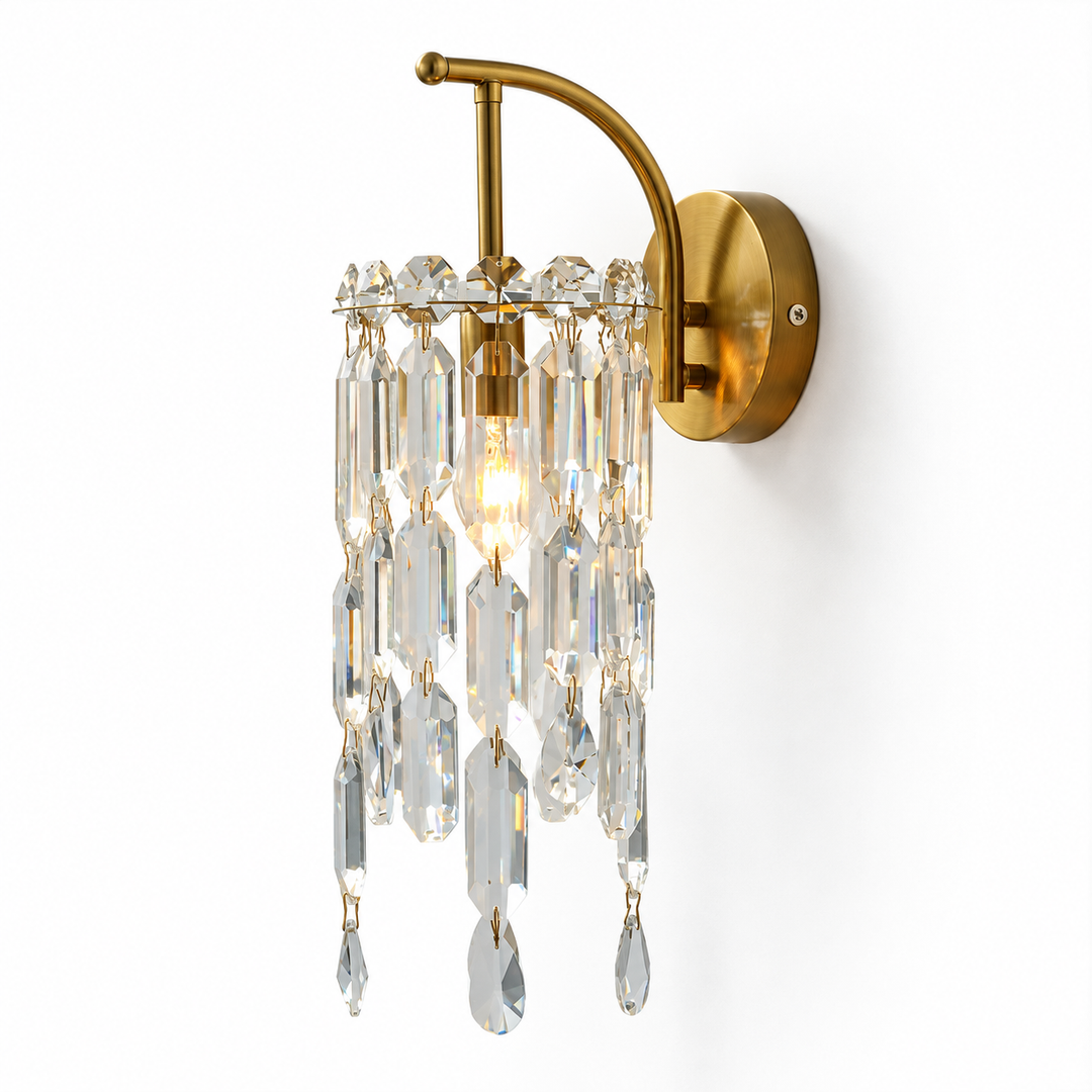 A wall-mounted brass sconce with clear hanging crystal prisms, shown against a plain white background.