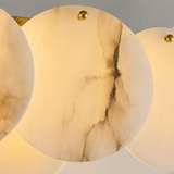 Close-up of the linear chandelier shows overlapping cream alabaster discs with dark veining and small brass fasteners.