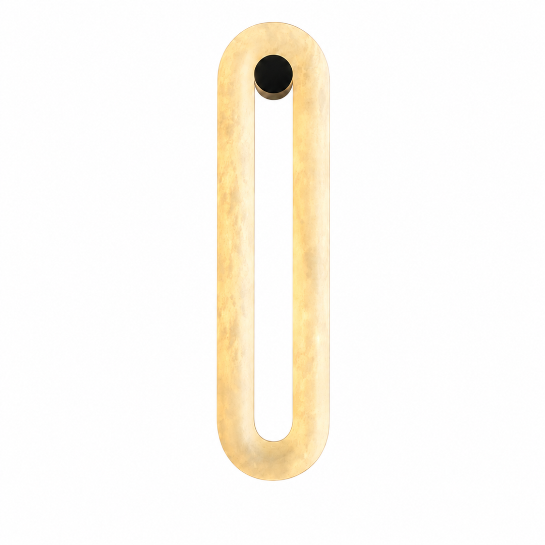 A modern, minimalist wall sconce featuring a vertical, elongated oval frame in a textured, warm gold finish with a small black circular accent at the top, shown against a solid white background.