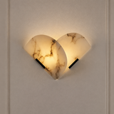 Wall sconce with overlapping cream alabaster panels, brown veining and black iron supports glows warmly against a pale paneled wall.